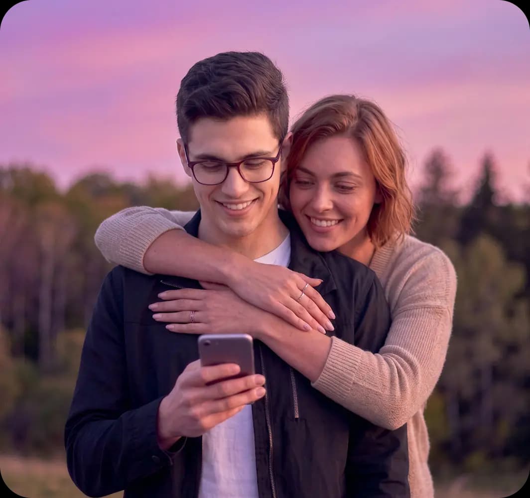 Mosolygó pár mobiltelefonnal.