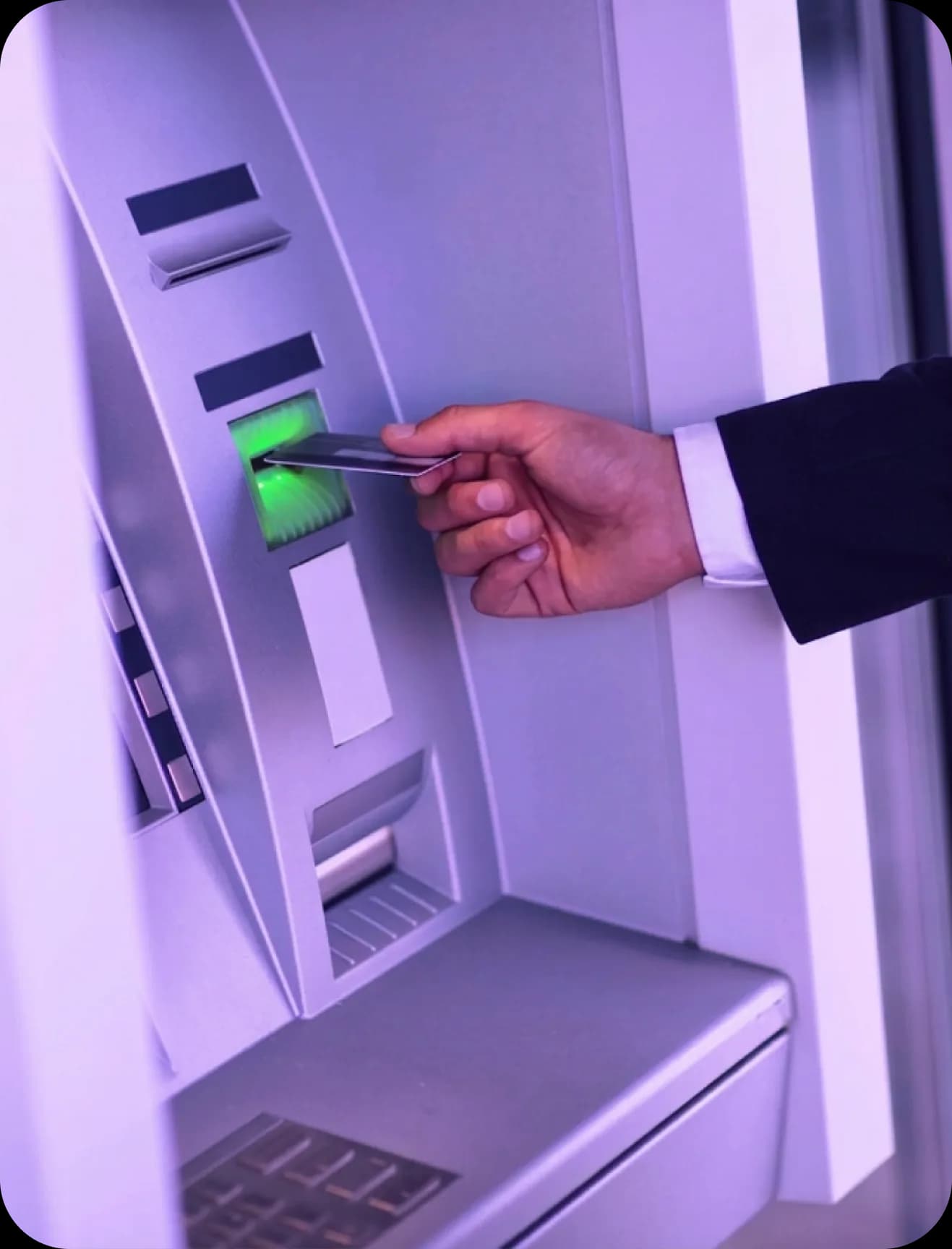 Bankkártyát ATM nyílásába helyező kéz közelről.