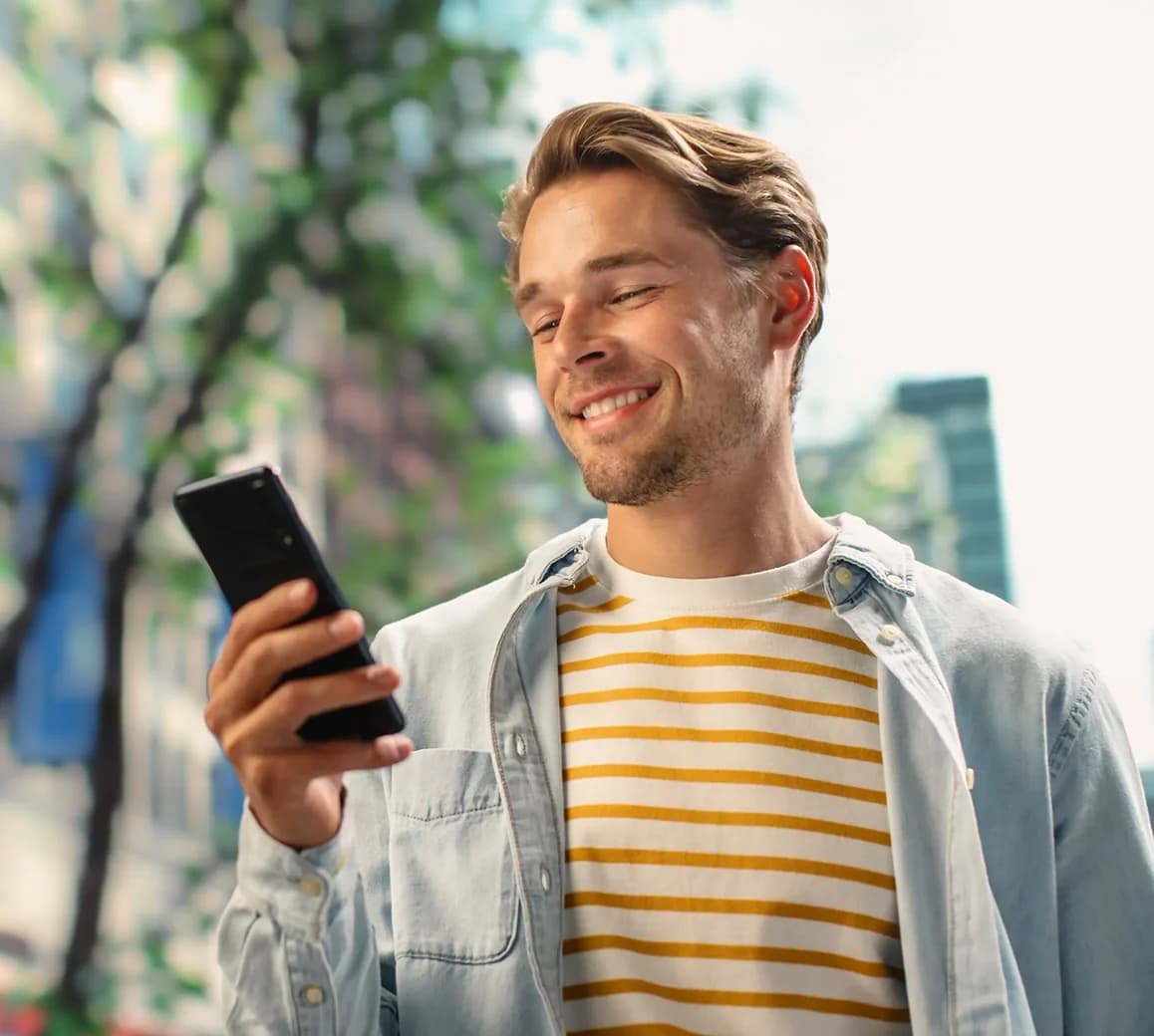 Fiatal férfi telefonját nézi.