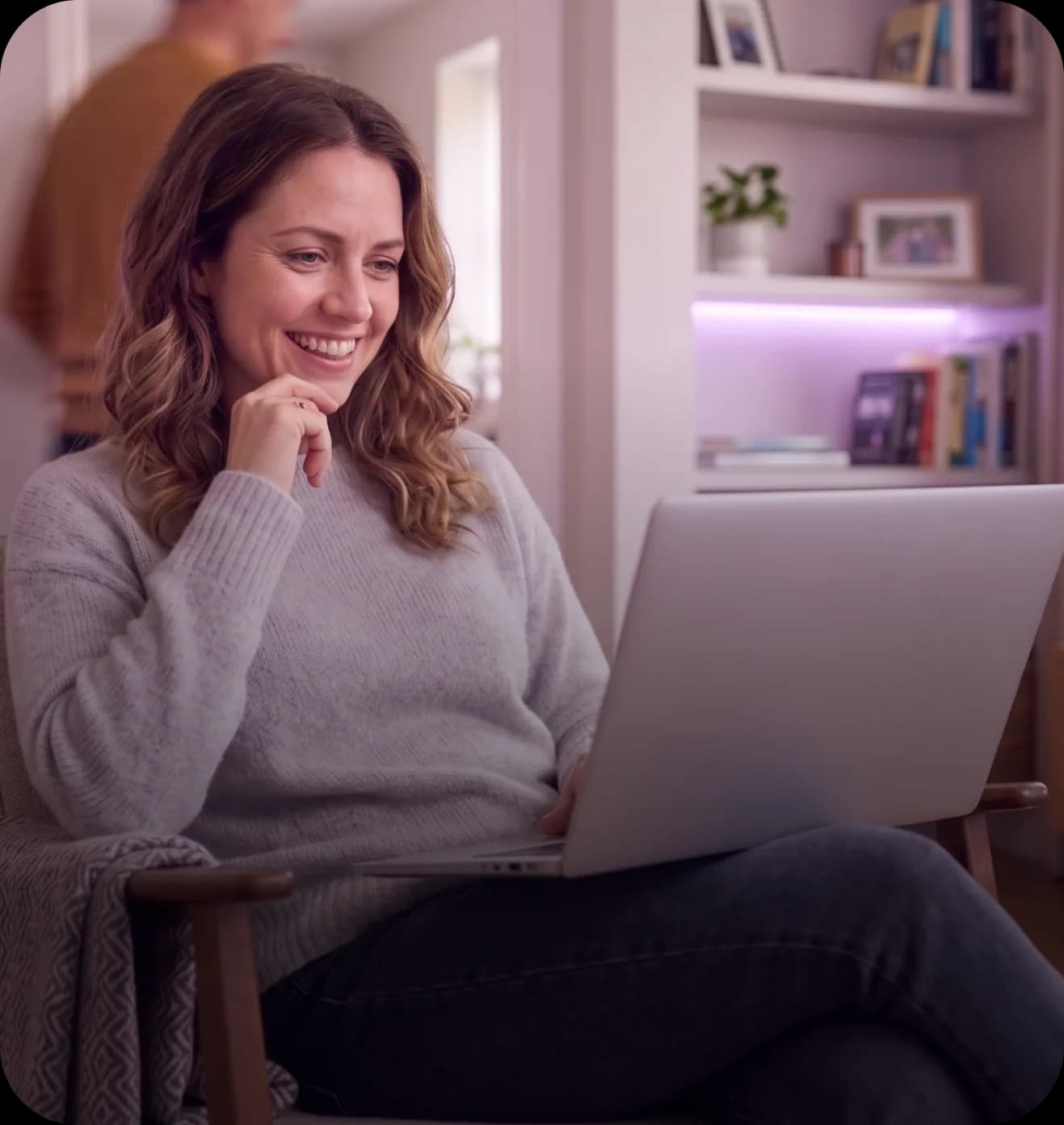 Fiatal nő mosolyogva dolgozik a laptopján.