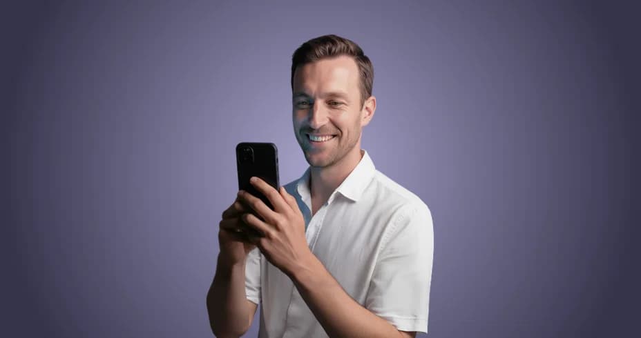 Mosolygó férfi a telefonját nézi