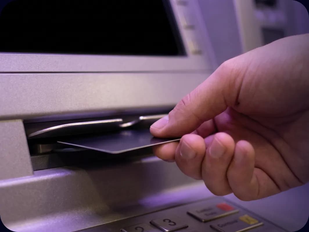 Kéz bankkártyát helyez egy ATM kártyanyílásába